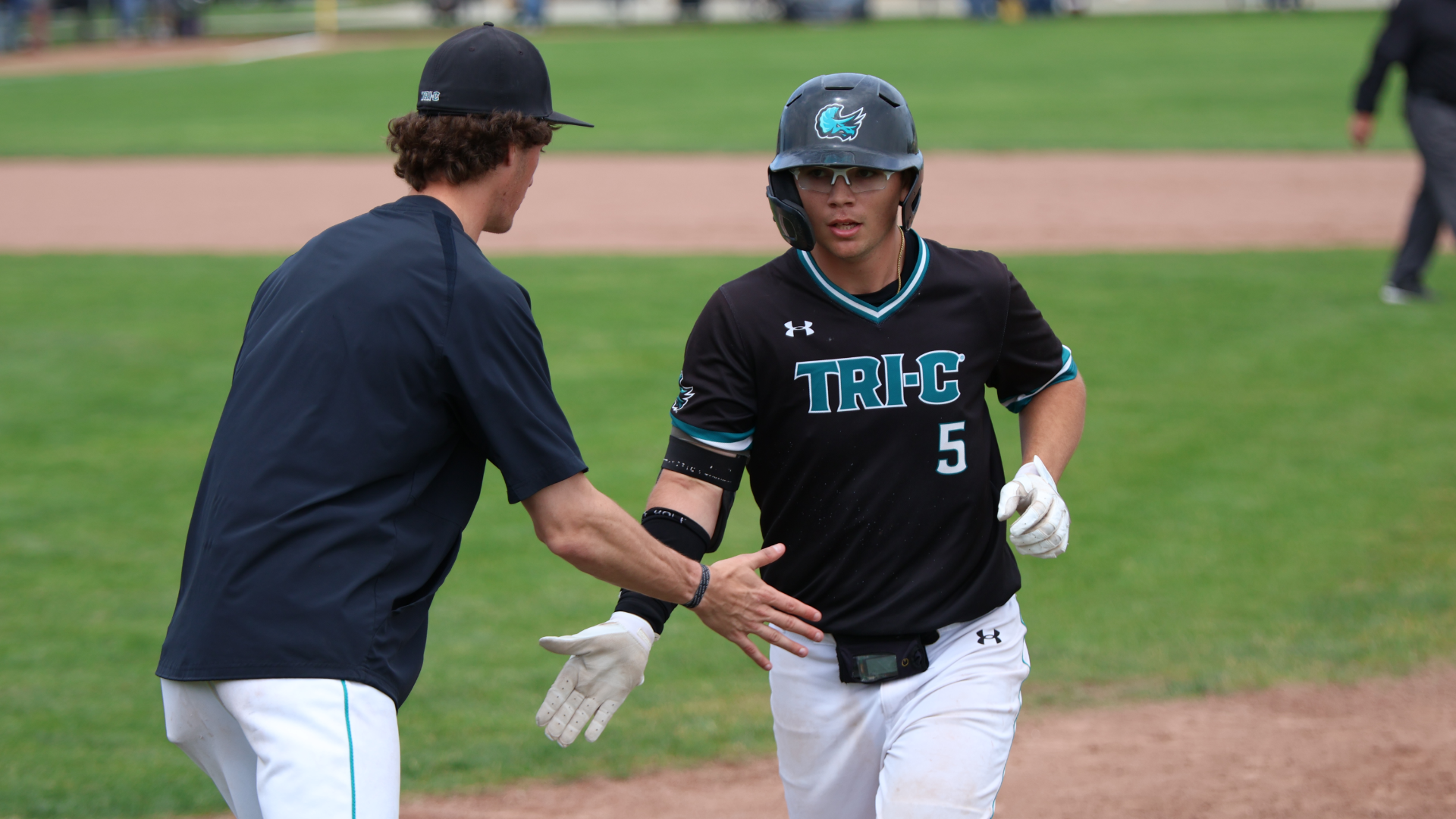 Two Tri-C baseball players high-fiving in a game
