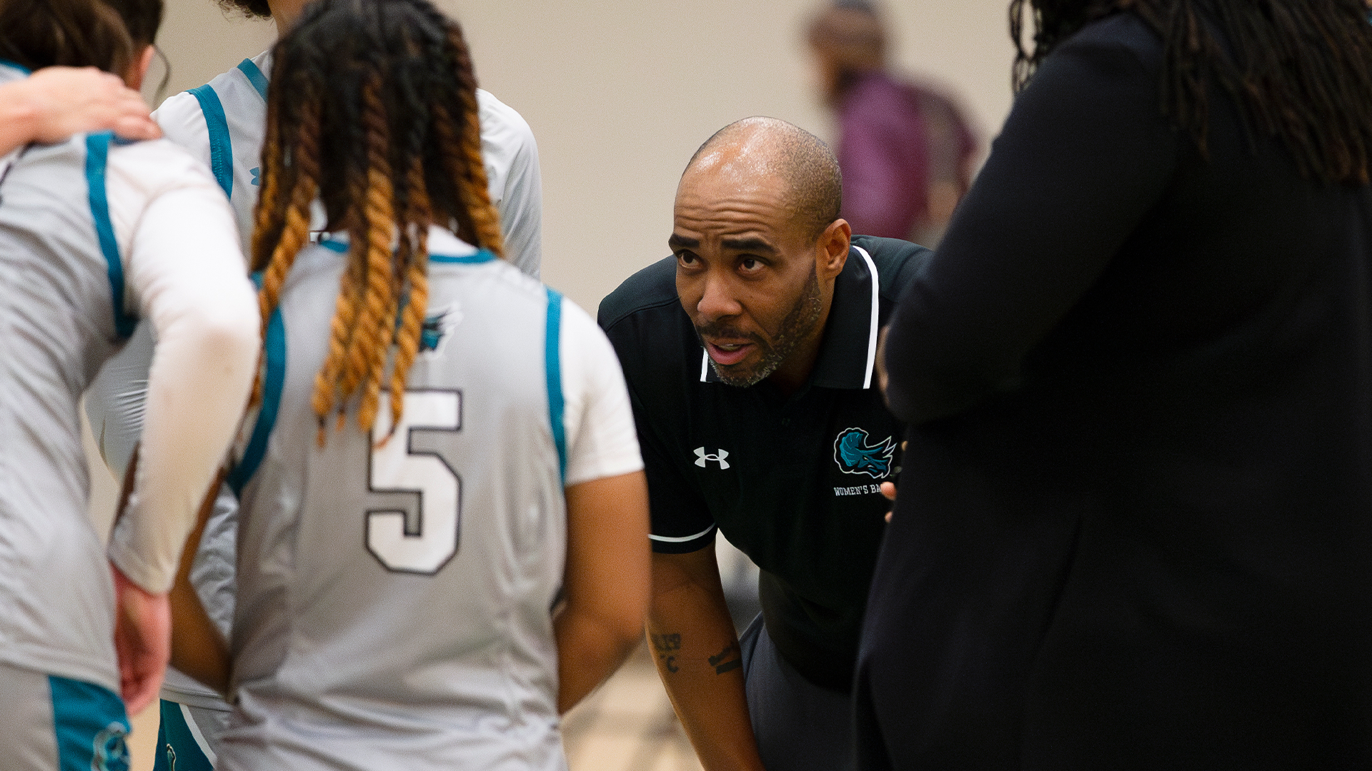 Tri-C women's basketball head coach Dion Griffin speaks to his team in a huddle during a game.